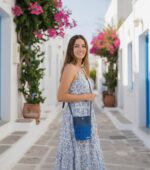 Η τσάντα Maraia φορεμένη χιαστί σε καλοκαιρινό σοκάκι δίπλα σε νησιώτικη αρχιτεκτονική