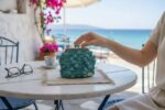 πλεκτό πορτοφολάκι nadine πάνω σε τραπέζι με θέα τη θάλασσα