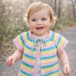 Μωρό που φορά πλεκτή ζακέτα ALINA σε pastel πολύχρωμες ρίγες σε εξωτερικό χώρο